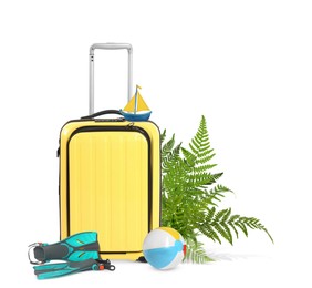 Yellow travel suitcase, tropical leaves, swim fins, toy sailboat and beach ball on white background