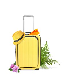 Yellow travel suitcase, paper plane, hat, tropical leaves and flowers on white background