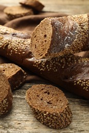 Photo of Fresh baguettes with sesame on wooden table, closeup