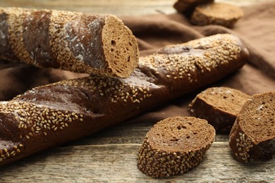 Photo of Fresh baguettes with sesame on wooden table, closeup