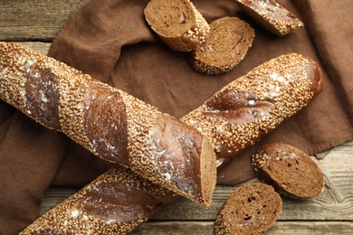 Photo of Fresh baguettes with sesame on wooden table, flat lay