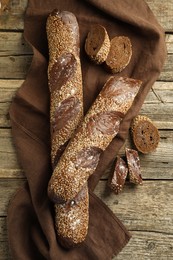 Photo of Fresh baguettes with sesame on wooden table, flat lay