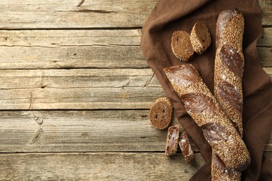 Photo of Fresh baguettes with sesame on wooden table, flat lay. Space for text