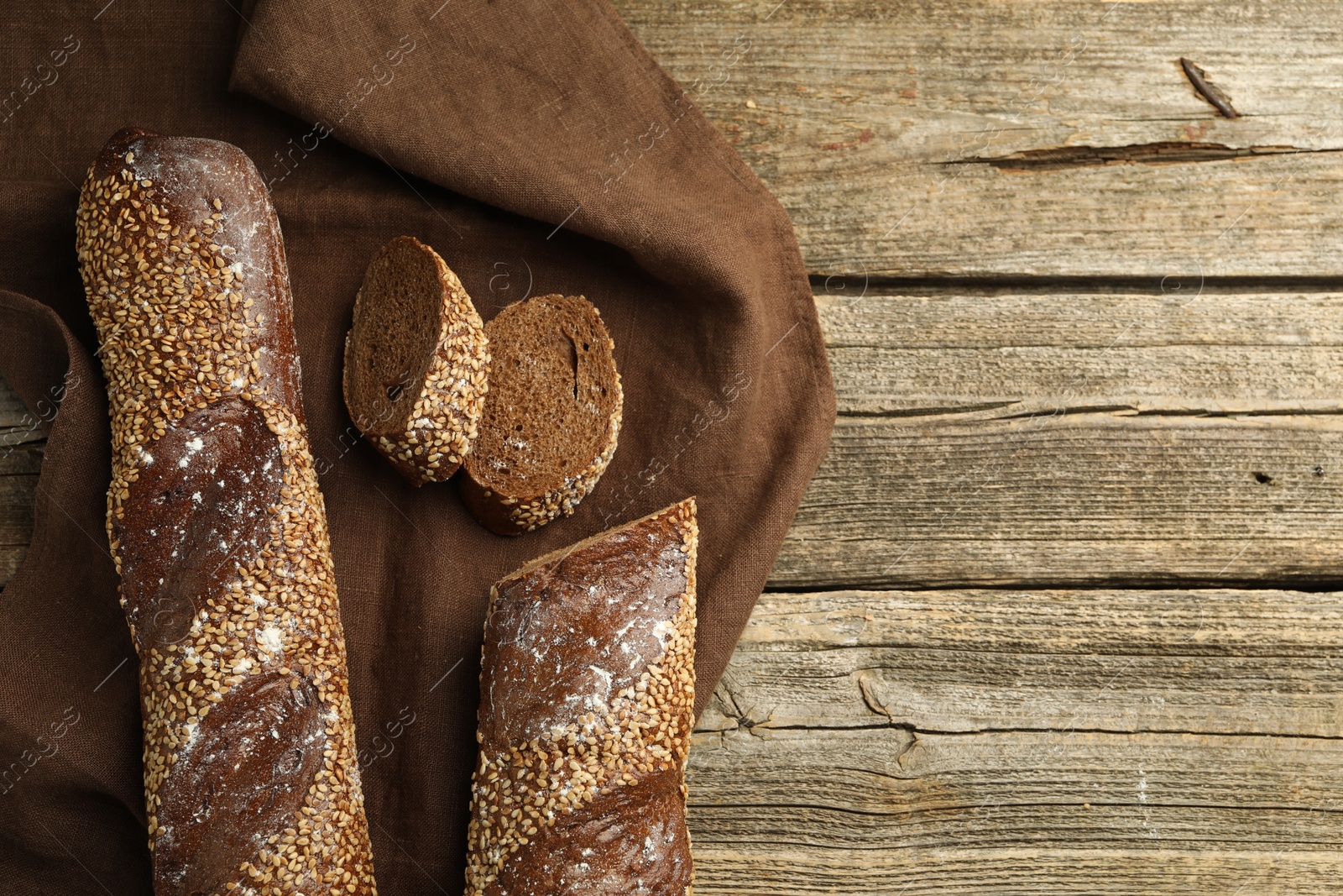 Photo of Fresh baguettes with sesame on wooden table, flat lay. Space for text