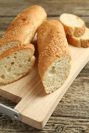 Photo of Cut fresh baguette with sesame on wooden table, closeup