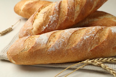 Photo of Fresh baguettes and spikes on beige table, closeup