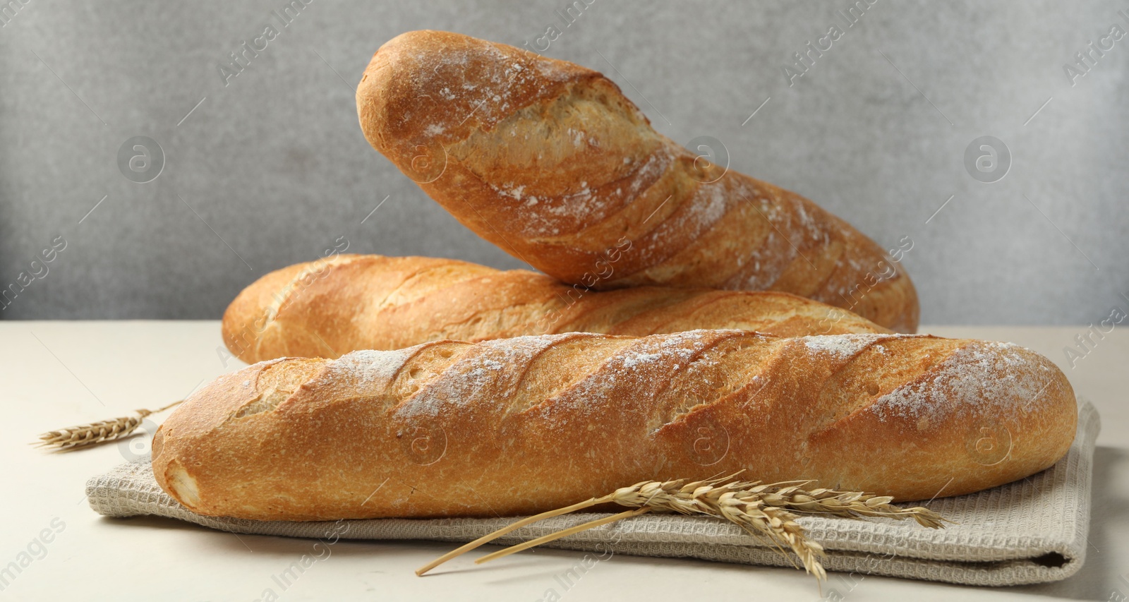 Photo of Fresh baguettes and spikes on beige table, closeup