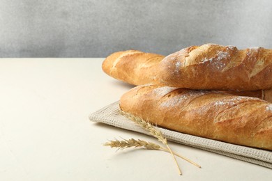 Photo of Fresh baguettes and spikes on beige table, space for text