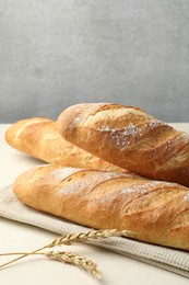 Photo of Fresh baguettes and spikes on beige table, closeup