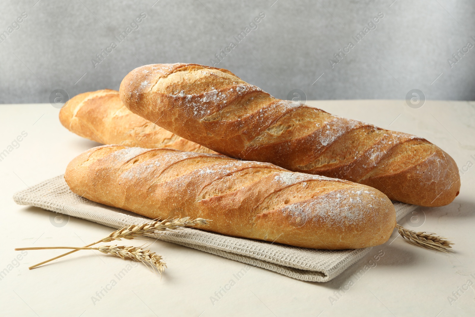 Photo of Fresh baguettes and spikes on beige table