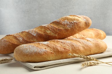 Photo of Fresh baguettes and spikes on beige table, closeup