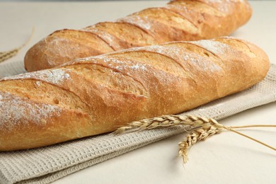 Photo of Fresh baguettes and spikes on beige table, closeup