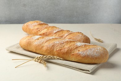 Photo of Fresh baguettes and spikes on beige table