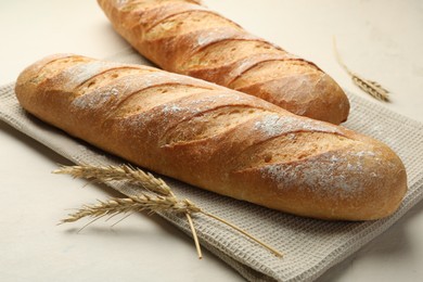 Photo of Fresh baguettes and spikes on beige table, closeup