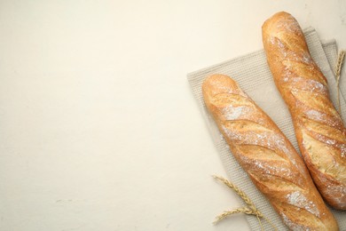 Photo of Fresh baguettes and spikes on beige table, flat lay. Space for text