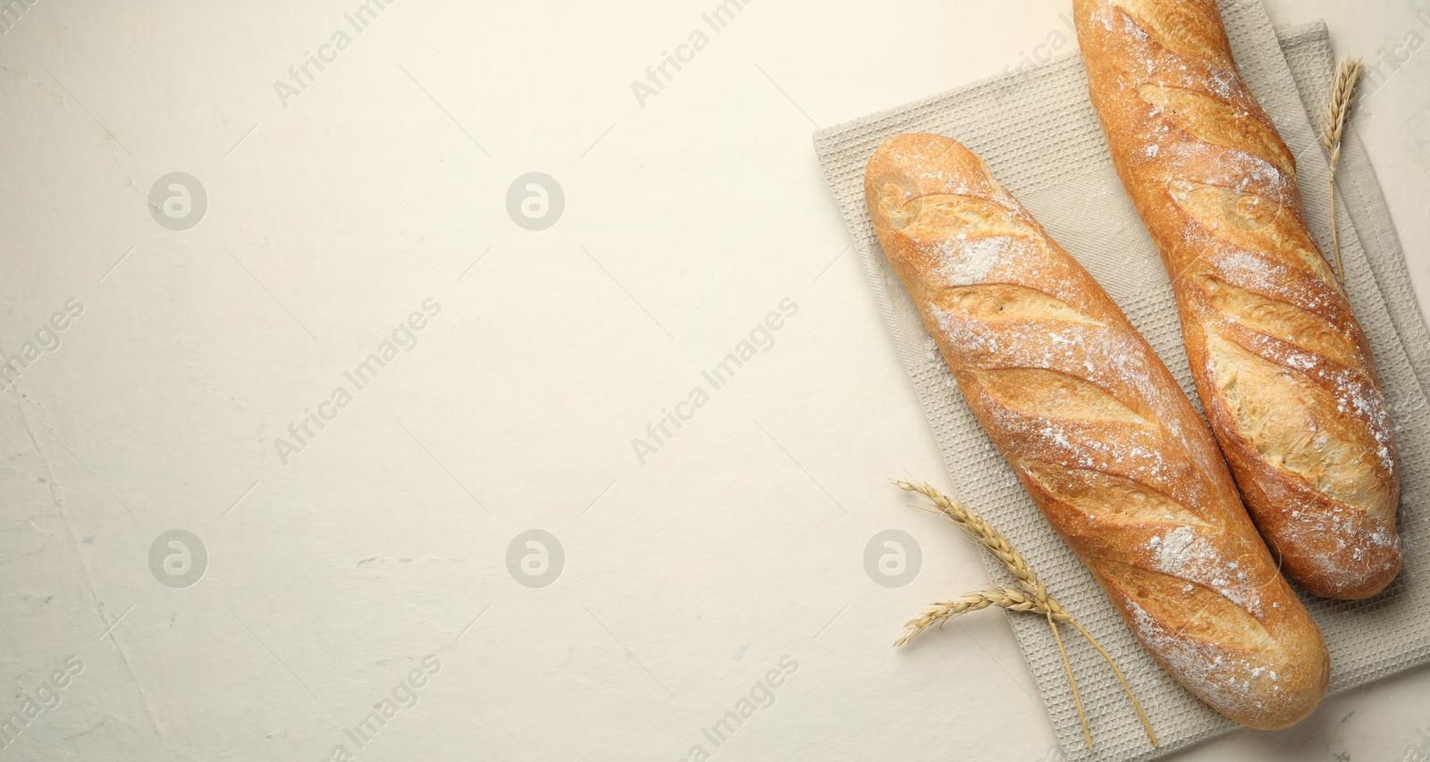 Photo of Fresh baguettes and spikes on beige table, flat lay. Space for text