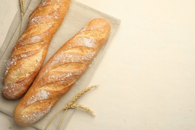 Photo of Fresh baguettes and spikes on beige table, flat lay. Space for text