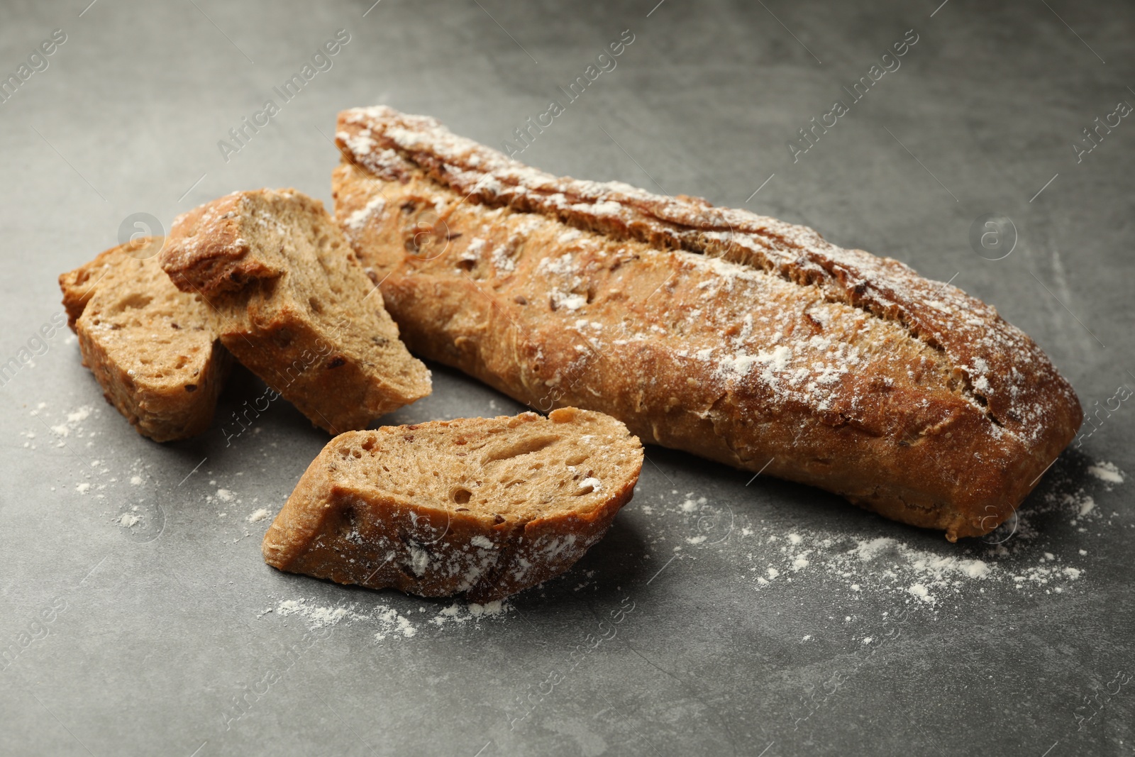 Photo of Pieces of fresh baguette on grey table