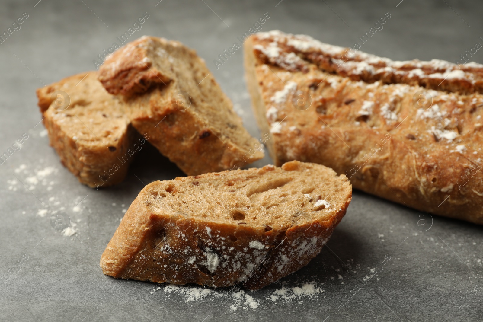 Photo of Cut fresh baguette on grey table, closeup