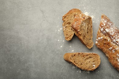 Photo of Cut fresh baguette on grey table, flat lay. Space for text