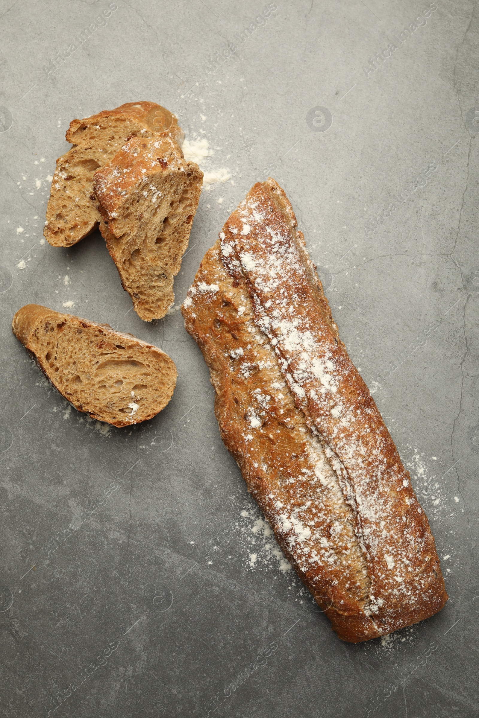 Photo of Cut fresh baguette on grey table, flat lay