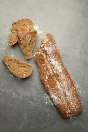 Photo of Cut fresh baguette on grey table, flat lay