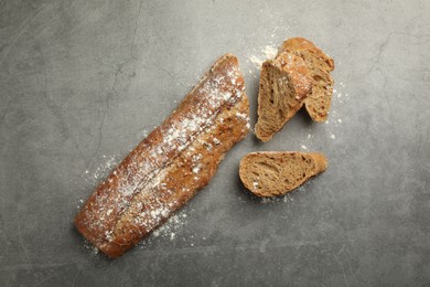 Photo of Cut fresh baguette on grey table, flat lay