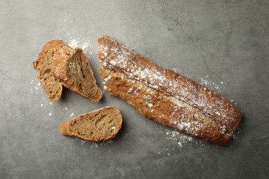 Photo of Cut fresh baguette on grey table, flat lay