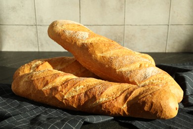 Photo of Freshly baked baguettes on black table, closeup