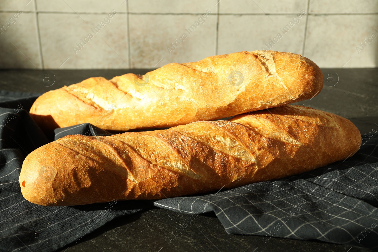 Photo of Freshly baked baguettes on black table, closeup