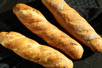 Photo of Freshly baked baguettes on black table, flat lay