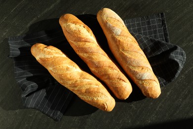 Freshly baked baguettes on black table, flat lay