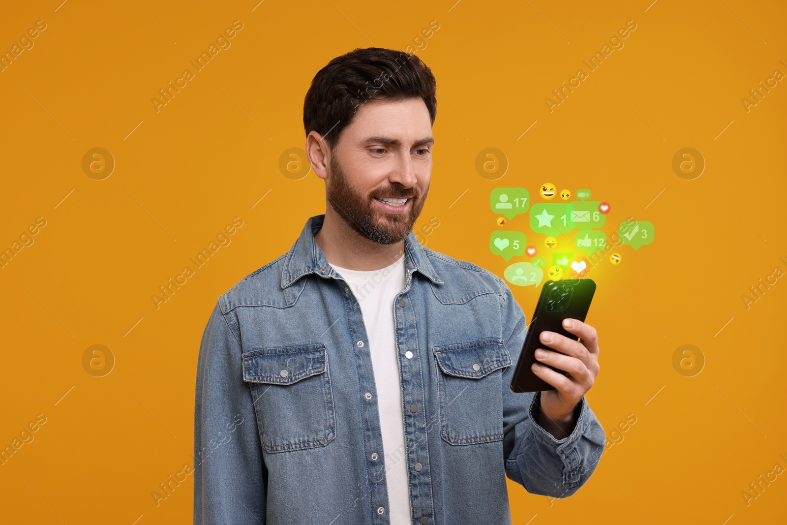 Image of Happy man using mobile phone on orange background. New message sign and other notifications over gadget