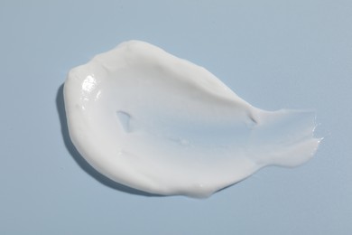 Photo of Sample of cream on light blue background, closeup. Cosmetic product