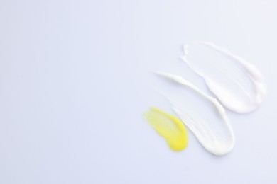 Photo of Samples of cosmetic products on white background, top view. Space for text