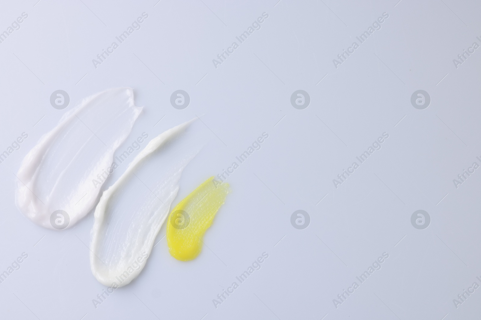 Photo of Samples of cosmetic products on white background, top view. Space for text