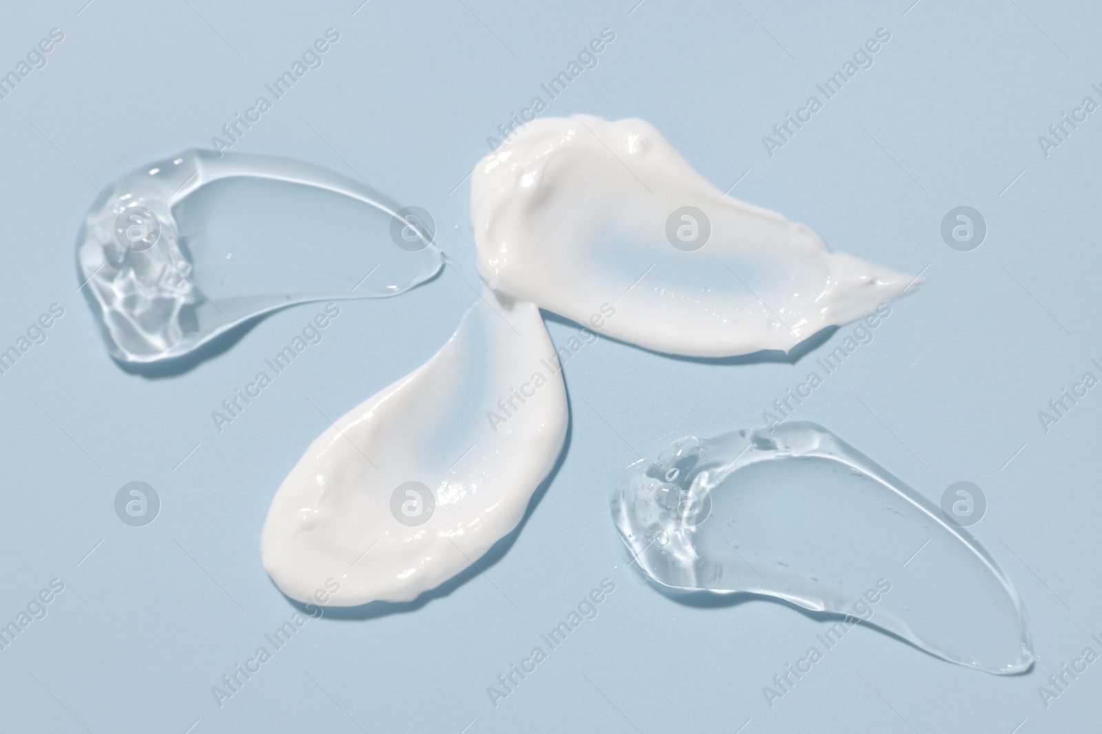 Photo of Samples of cosmetic products on light blue background, closeup