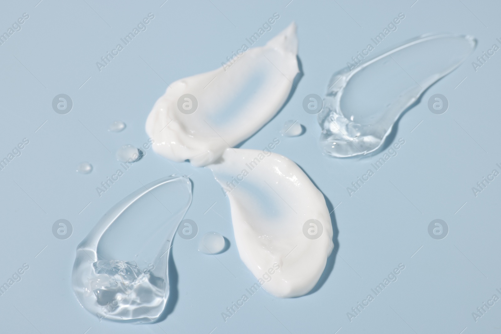 Photo of Samples of cosmetic products on light blue background, closeup