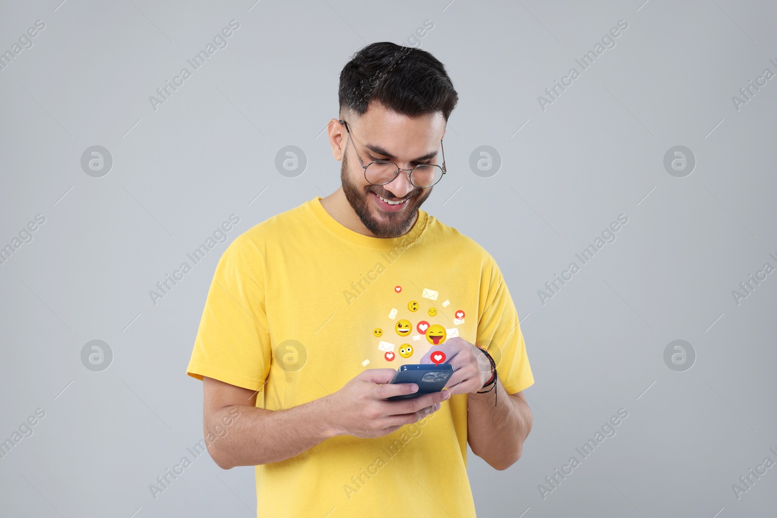 Image of Happy man using mobile phone on light grey background. New message sign and other notifications over gadget