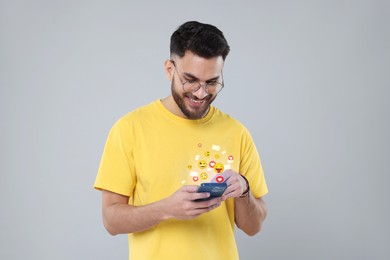 Image of Happy man using mobile phone on light grey background. New message sign and other notifications over gadget