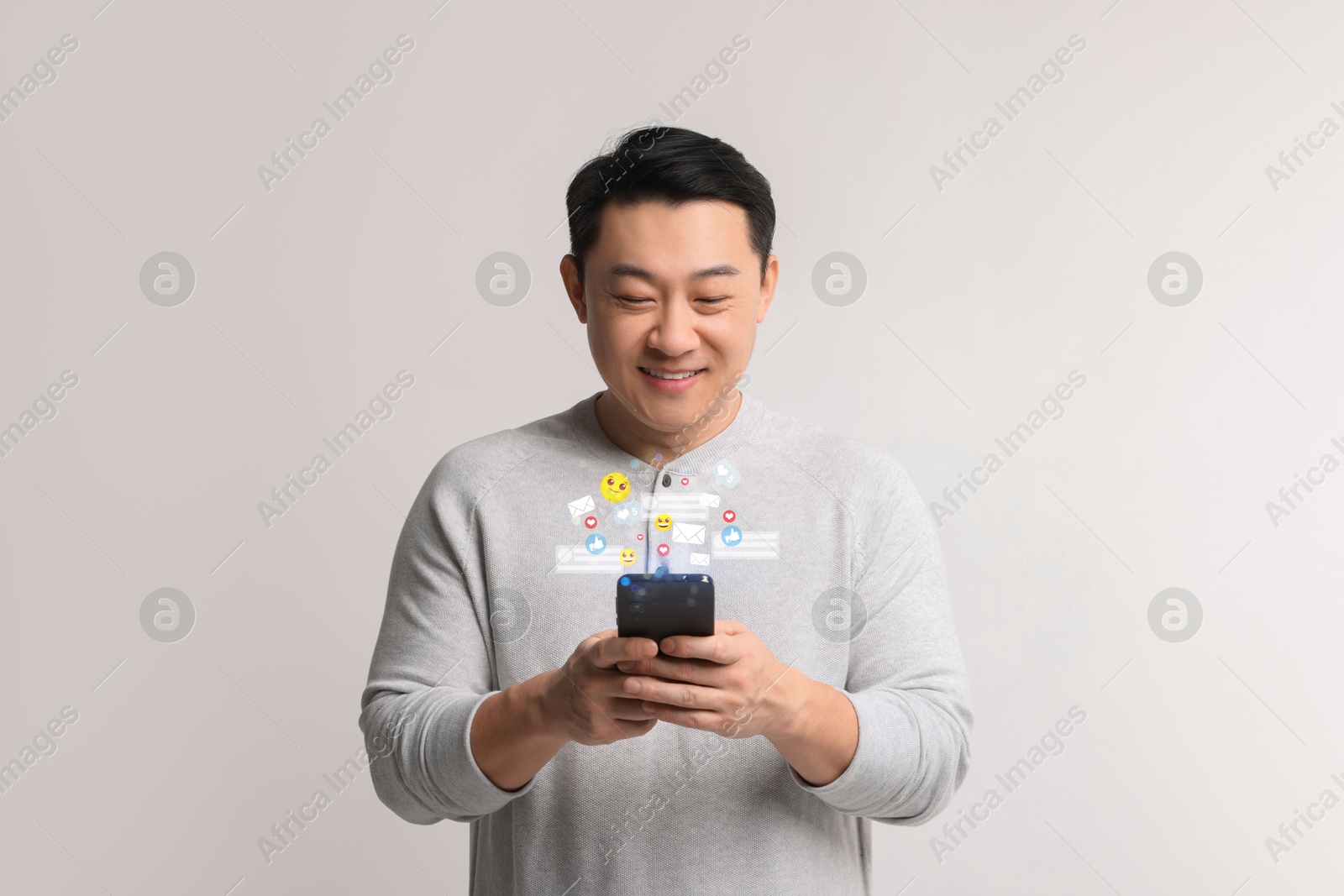 Image of Happy man using mobile phone on light grey background. New message sign and other notifications over gadget