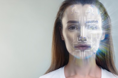 Facial and iris recognition system. Woman undergoing biometric verification on grey background