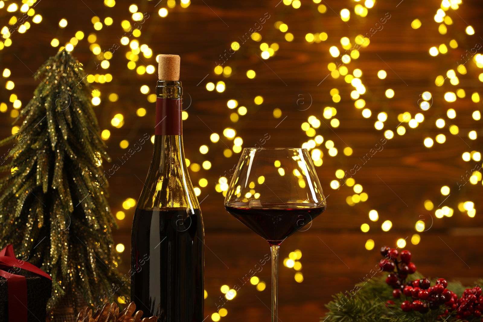 Photo of Red wine and Christmas decor against blurred lights, closeup