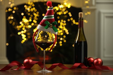 Glass of red wine and Christmas decor on wooden table against blurred lights