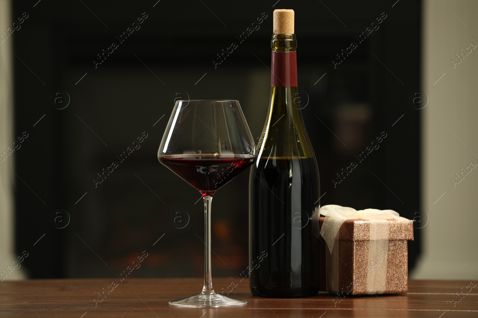 Photo of Red wine and Christmas present on wooden table indoors