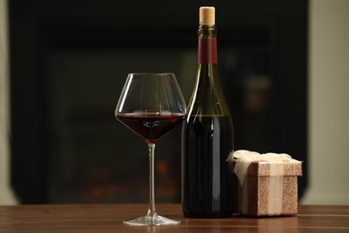 Photo of Red wine and Christmas present on wooden table indoors