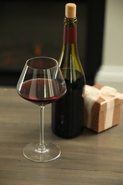 Photo of Red wine and Christmas present on wooden table indoors