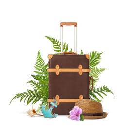 Brown travel suitcase, hat, toy anchor, seashell, tropical leaves and flower on white background