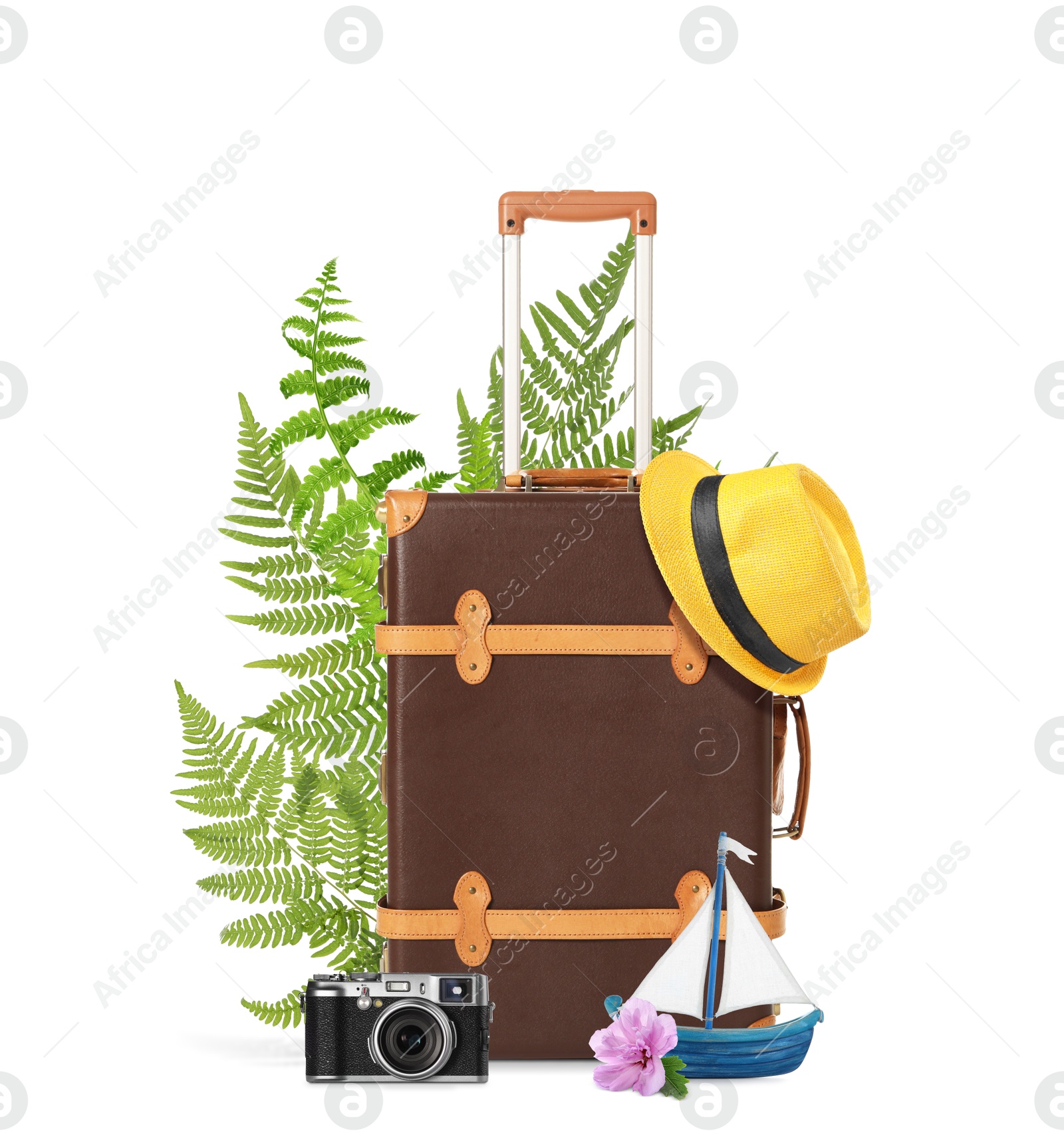 Image of Brown travel suitcase, hat, camera, toy sailboat, tropical leaves and flower on white background