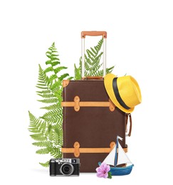 Image of Brown travel suitcase, hat, camera, toy sailboat, tropical leaves and flower on white background